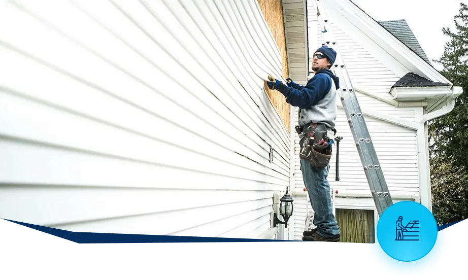 Contractor repairing residential siding using ladder on house exterior