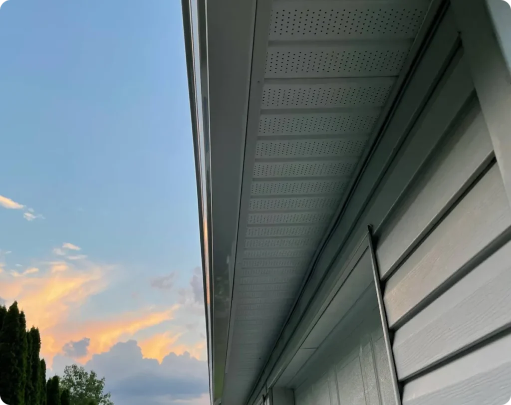 House roof soffit and gutter system at sunset sky view